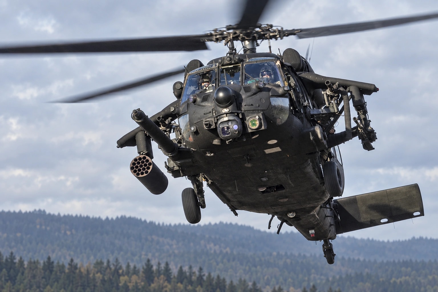 A Black Hawk DAP in flight over a distant tree line.